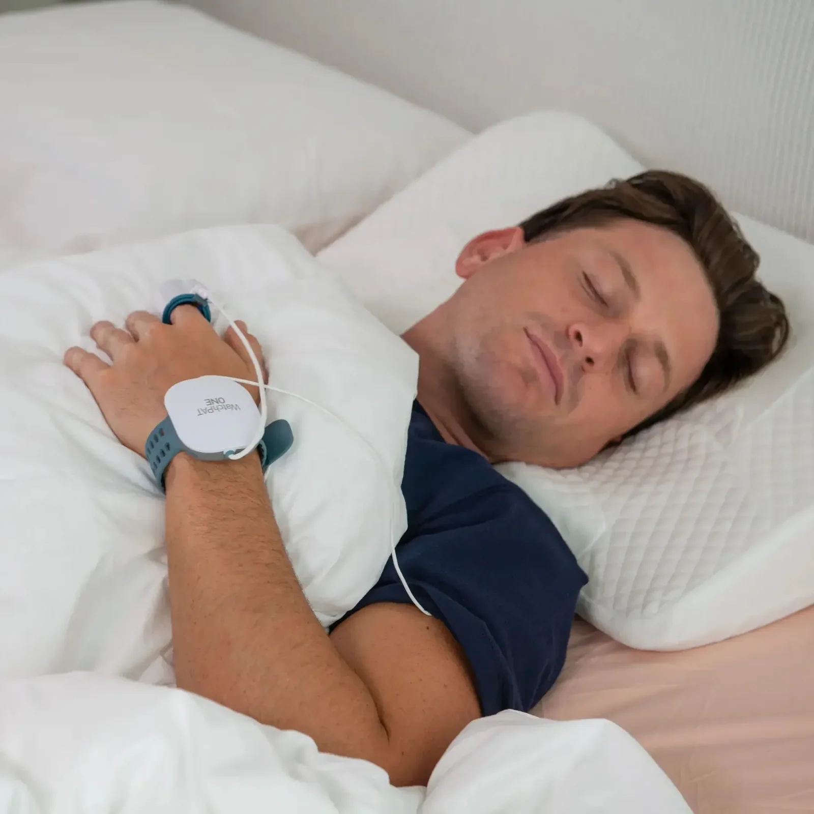 Man sleeping comfortably at home wearing a WatchPAT ONE home sleep test device
